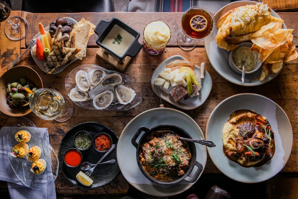 A wood table at The Tavern covered in dishes like oysters and more.
