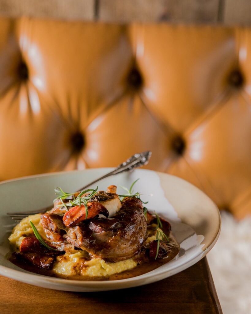 A bowl full of food on a table in front of a leather couch.