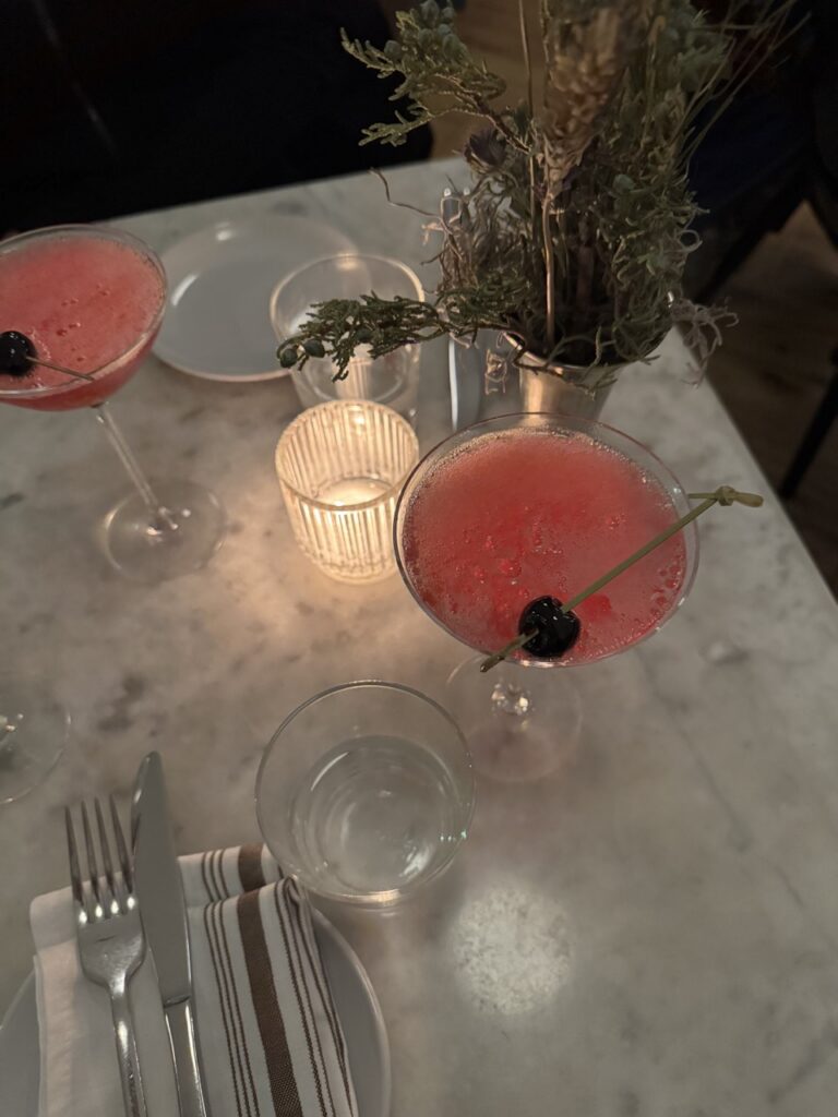 A pink cocktail sits on a white marble table.