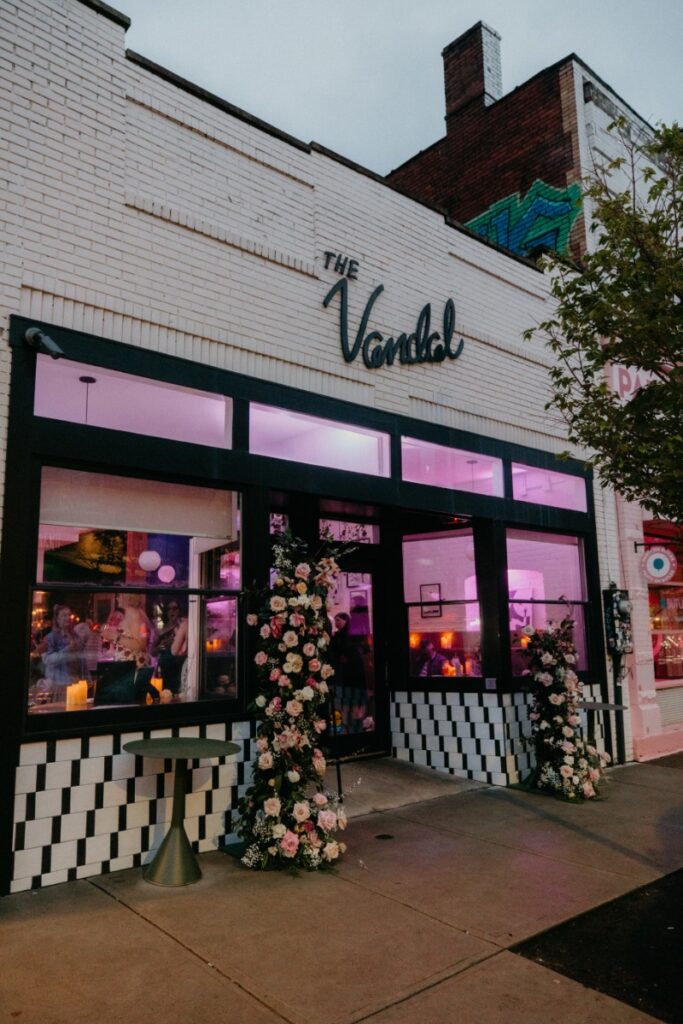 The exterior of The Vandal restaurant in Pittsburgh, featuring floral pillars and glowing pink lights for a private wedding renewal celebration.