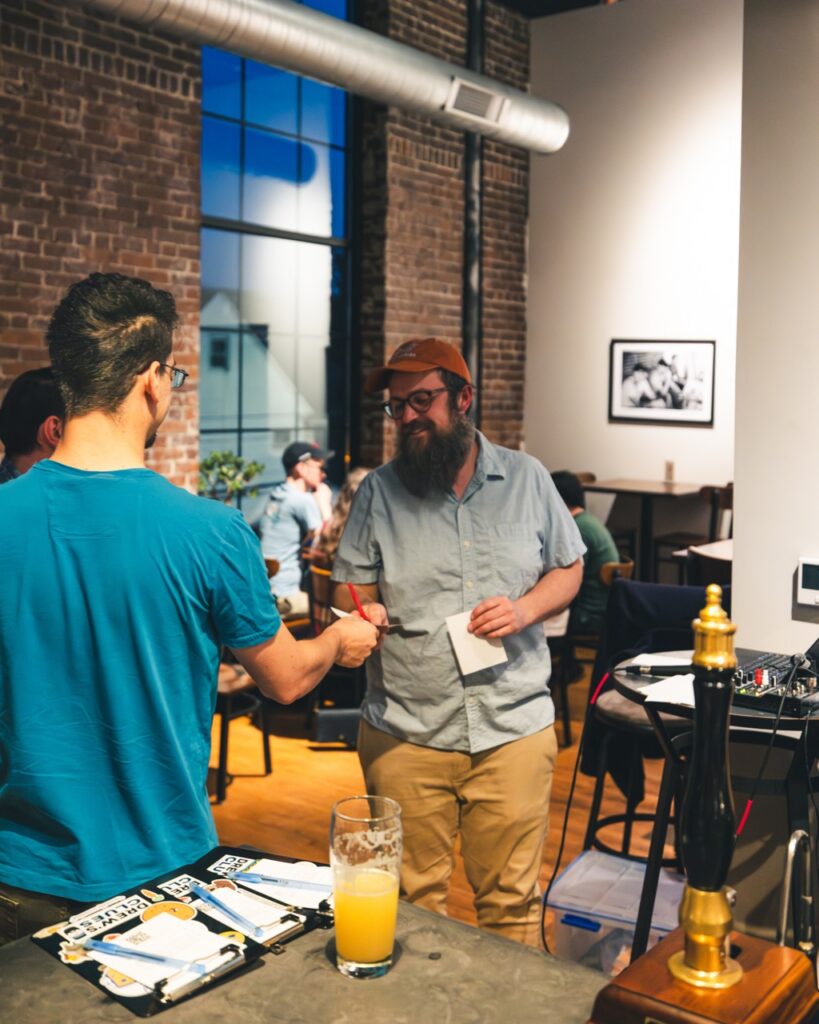 A man takes a trivia answer sheet from another.