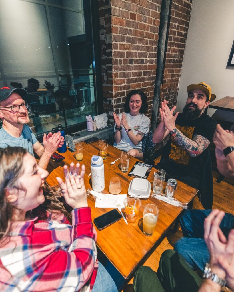 A group of contestants clap at their table.