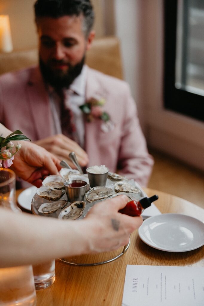 A waiter sets oysters down on a table.