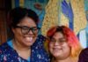 Building Hope at Home with Action Housing, Foster Love Project, and Family Links Two smiling women standing together in front of a colorful mosaic mural as part of a community human services initiative.