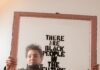 Alisha B. Wormsley Creates Socially Engaged Art in Pittsburgh Pittsburgh artist Alisha B. Wormsley holding an antique brown window frame featuring her iconic "There Are Black People In The Future" text, a key piece of her socially engaged art practice.