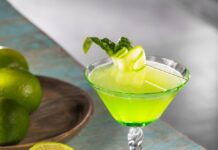 Basil Cucumber Spring Equinox Gimlet A green basil and cucumber gimlet in a Nick and Nora glass with half a lime sitting beside it.