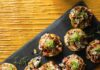 Blackened Cajun Chicken Tostada Small Blackened Cajun Chicken Tostadas sit on a black rectangular tray on top of a wood table.