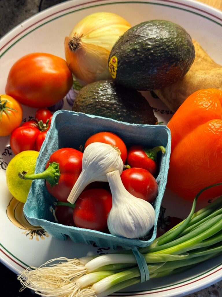 A basket of vegetables surrounded by other vegetables on a platter.