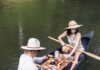 Hosting a Romantic Canoe Lunch Date A man and woman in hats sit in a canoe with a charcuterie plate between them.