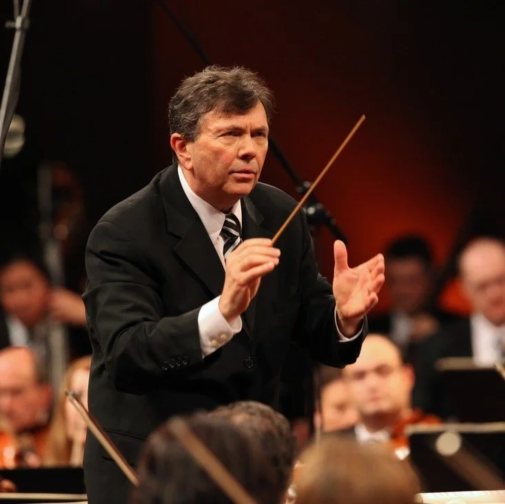 A man conducts the Carnegie Mellon Philharmonic with a baton.