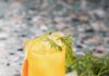 Carrot Moscow Mule A Carrot Moscow Mule in a yellow color sits on a white cloth with a carrot leaning against it.