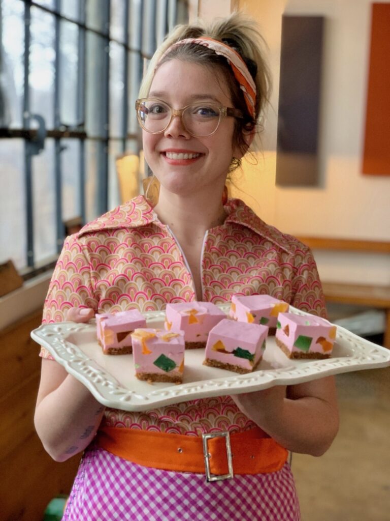 Casey Renee holds a tray of pink square confections.