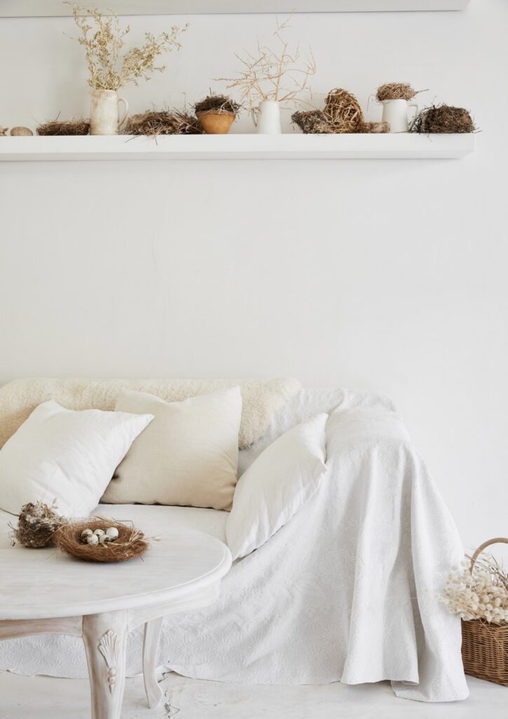 A white couch and table surround by various nests of eggs.
