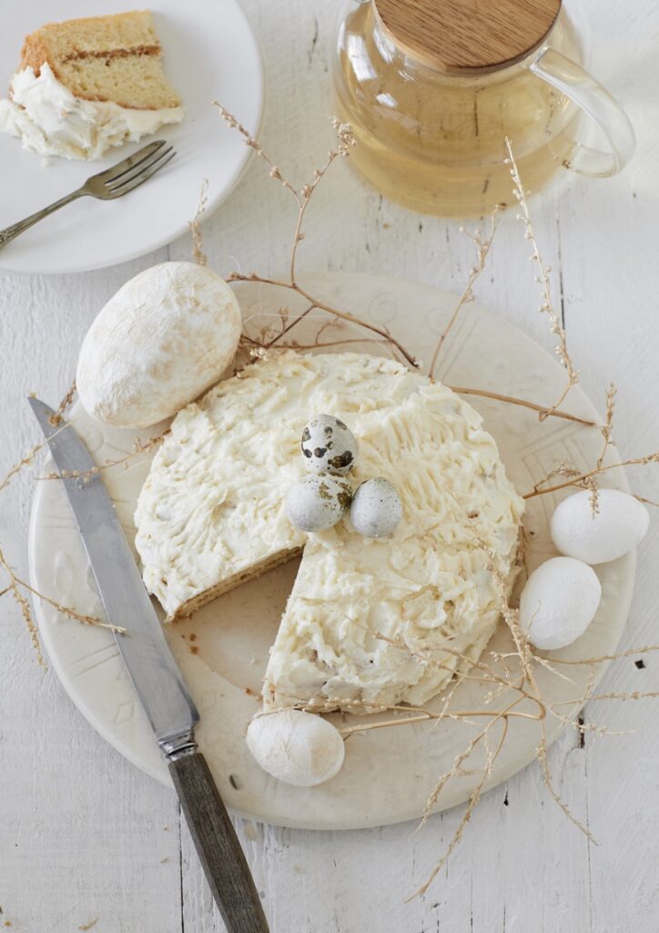 A cake in beige color with a slice taken out and eggs surrounding it.