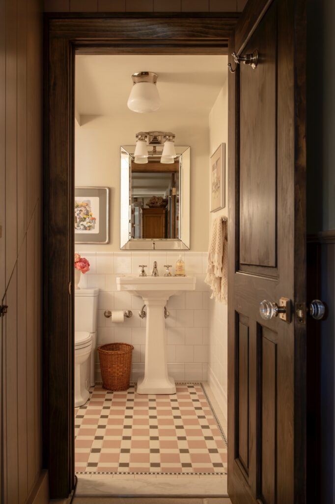 An inside shot of a bathroom showing a mirror and white sink on a tile floor.