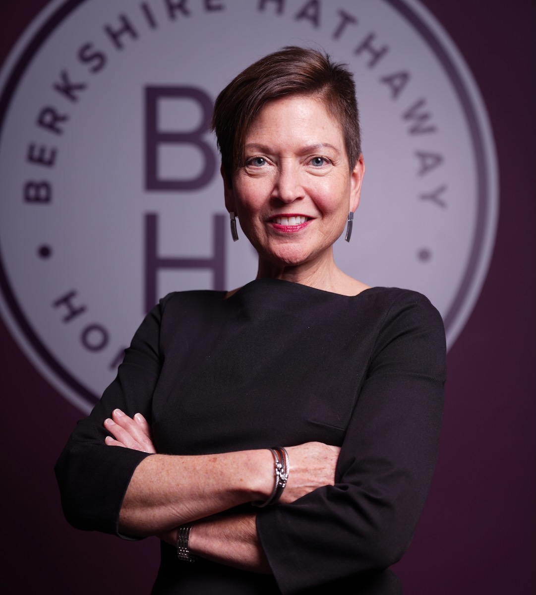 A woman in a black long sleeve shirt with short hair and earrings.