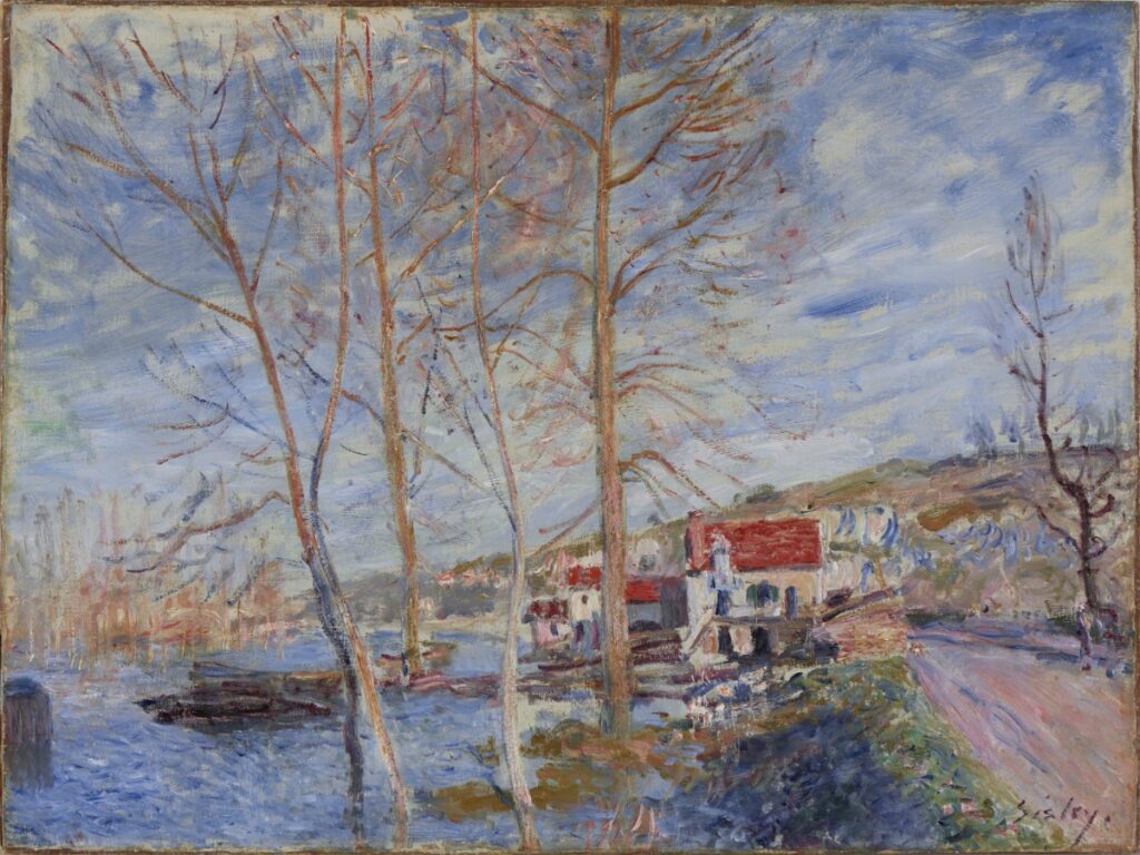An Impressionist landscape painting by Alfred Sisley featuring slender, bare trees along a riverbank with a red-roofed house and rolling hills under a blue, cloudy sky.