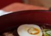 Hangover Homemade Ramen A bowl of hangover ramen with slices of pork, a soft boiled egg, and greens.