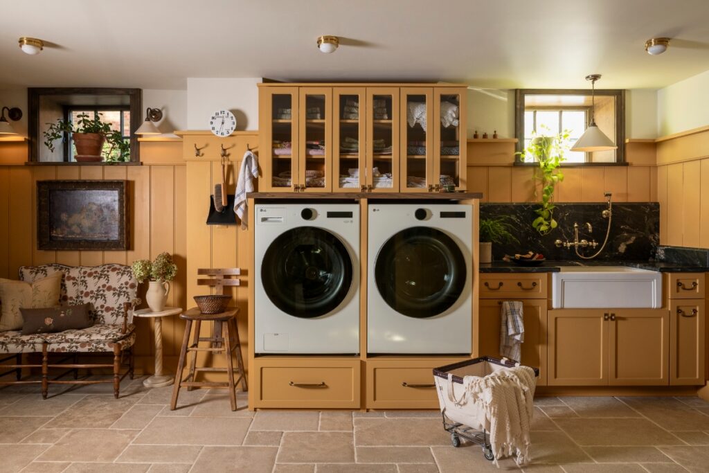 A stylish basement laundry room renovation featuring a modern washer and dryer set, cabinetry, and patterned tile floor.