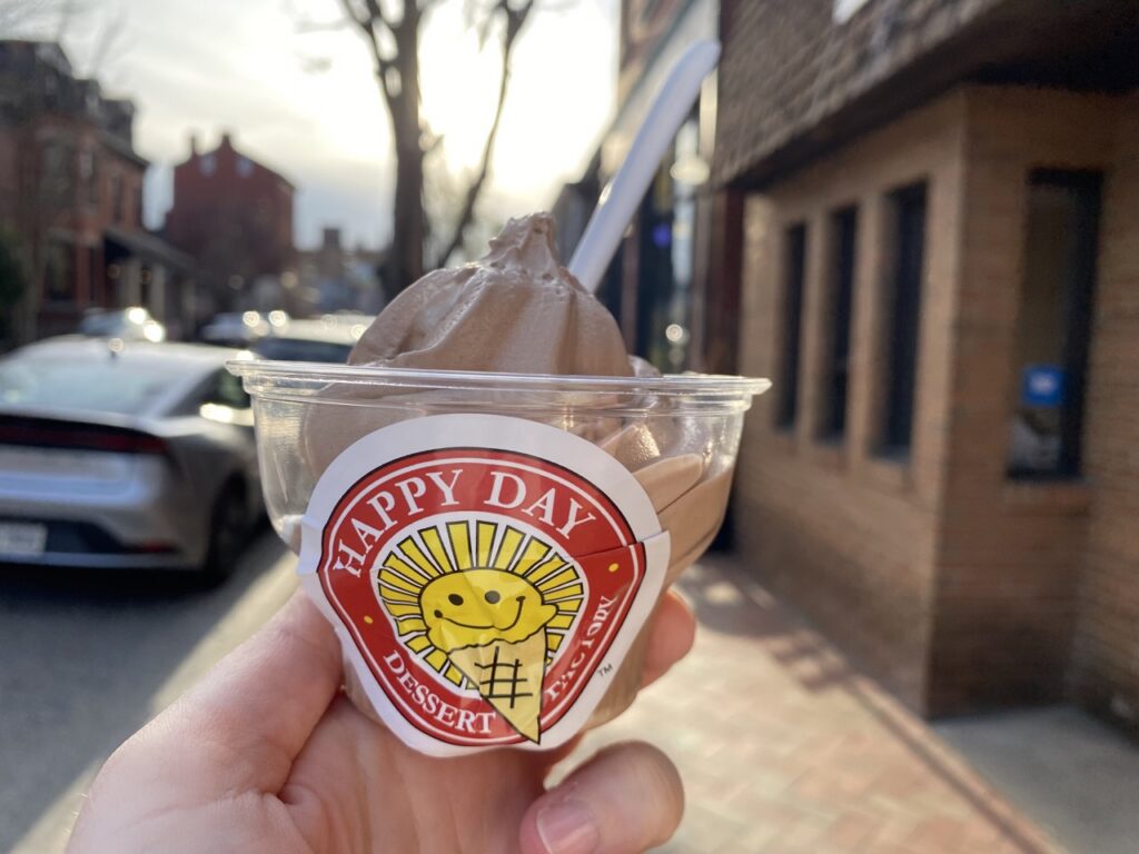 Chocolate soft serve in a small clear cup.