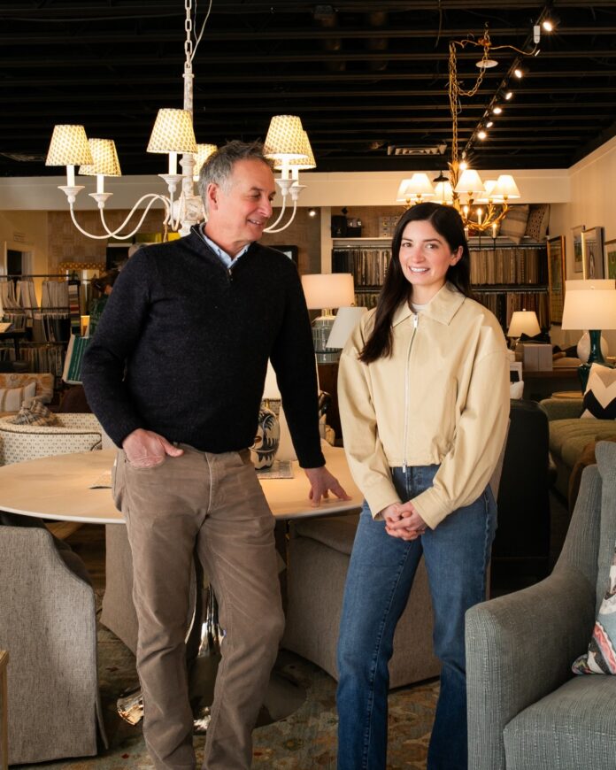 Jay Miller smiles at his daughter in a white sweater as he leans against a table.