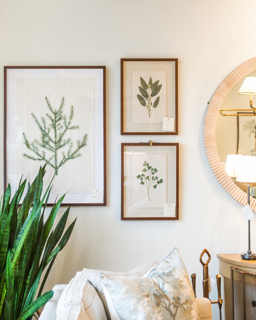 Three framed photos on a white wall next to a round mirror.