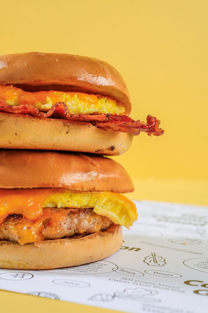 A stack of breakfast bagel sandwiches on a yellow background.