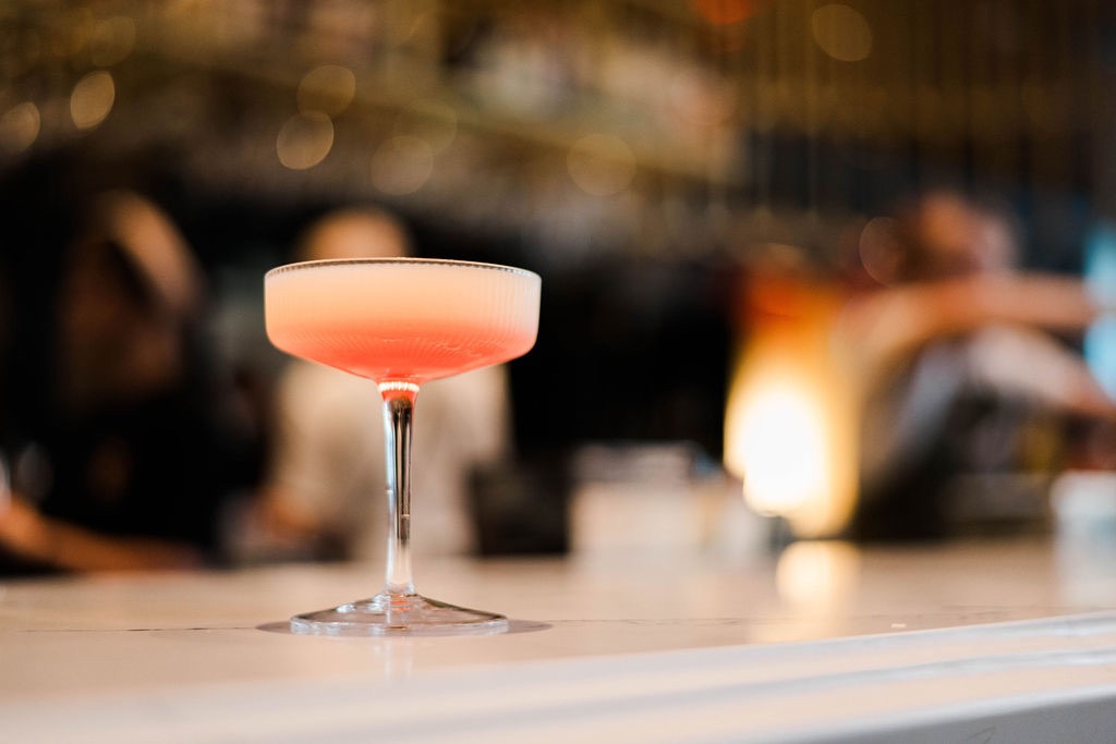 A cocktail glass on the Palm Palm bar with a pink liquid inside.