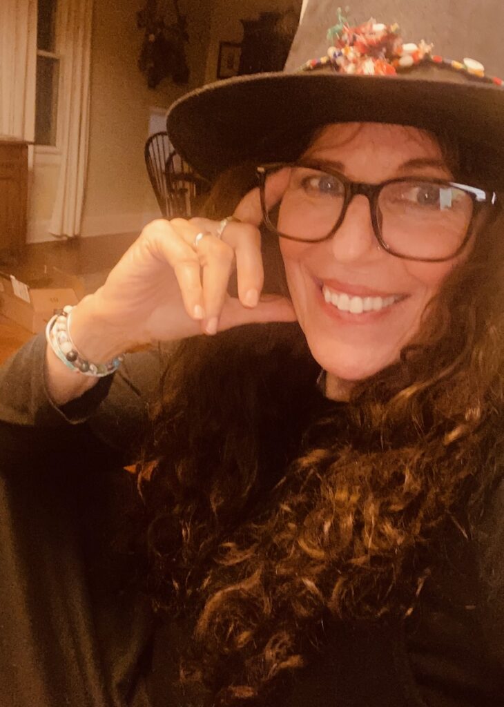 Liz Tamburri smiles in a hat and glasses. 