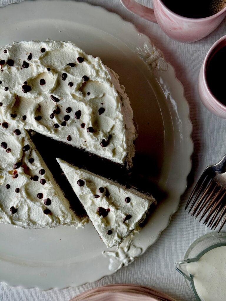 A white cake with chocolate chips over top. A slice is partially taken out.