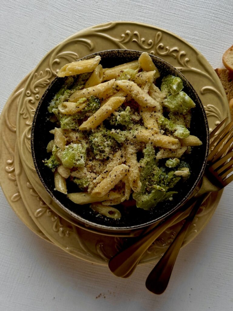 A bowl of mac and cheese with broccoli all through it.