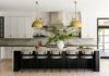 Modern California Style Transforms a Pittsburgh Family Home A bright California-cool kitchen in a Fox Chapel home featuring a large black island with a marble countertop, brass pendant lights, and white cabinetry designed by Elysa Roberts Interiors.