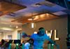 Your Guide for Food, Wine, and Fun North of Pittsburgh A person in a "City of Champyinz" t-shirt bowling on a neon-lit blue lane at AMF Mt. Lebanon Lanes.