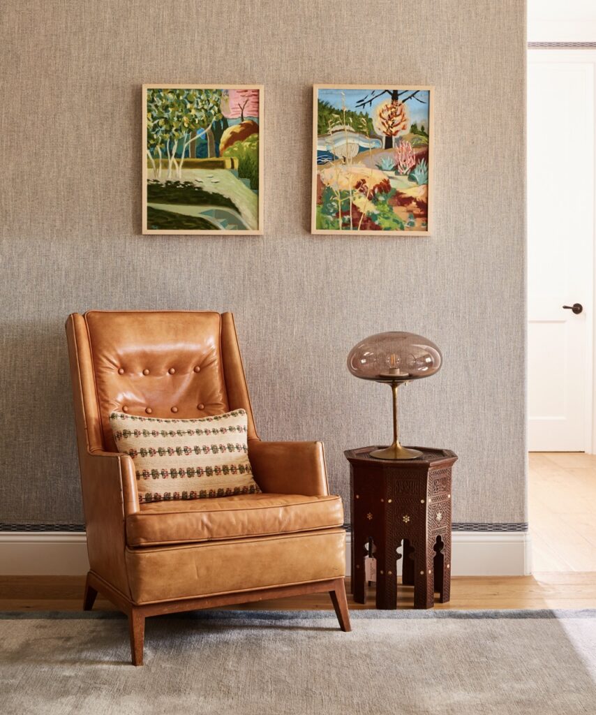 A tall brown leather chair sits beside a brown side table and lamp.