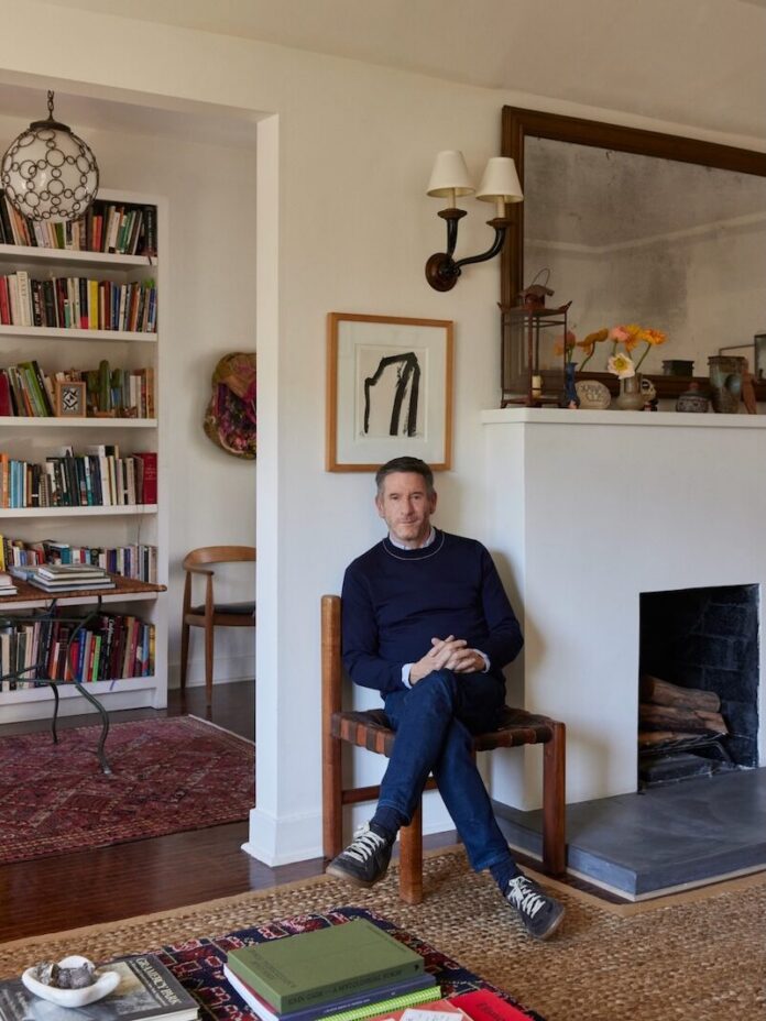Peter Dunham sits in a wooden chair inside the living room of his home.