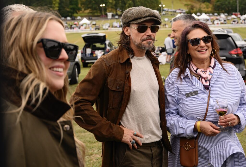 Three people smile in sunglasses outside.