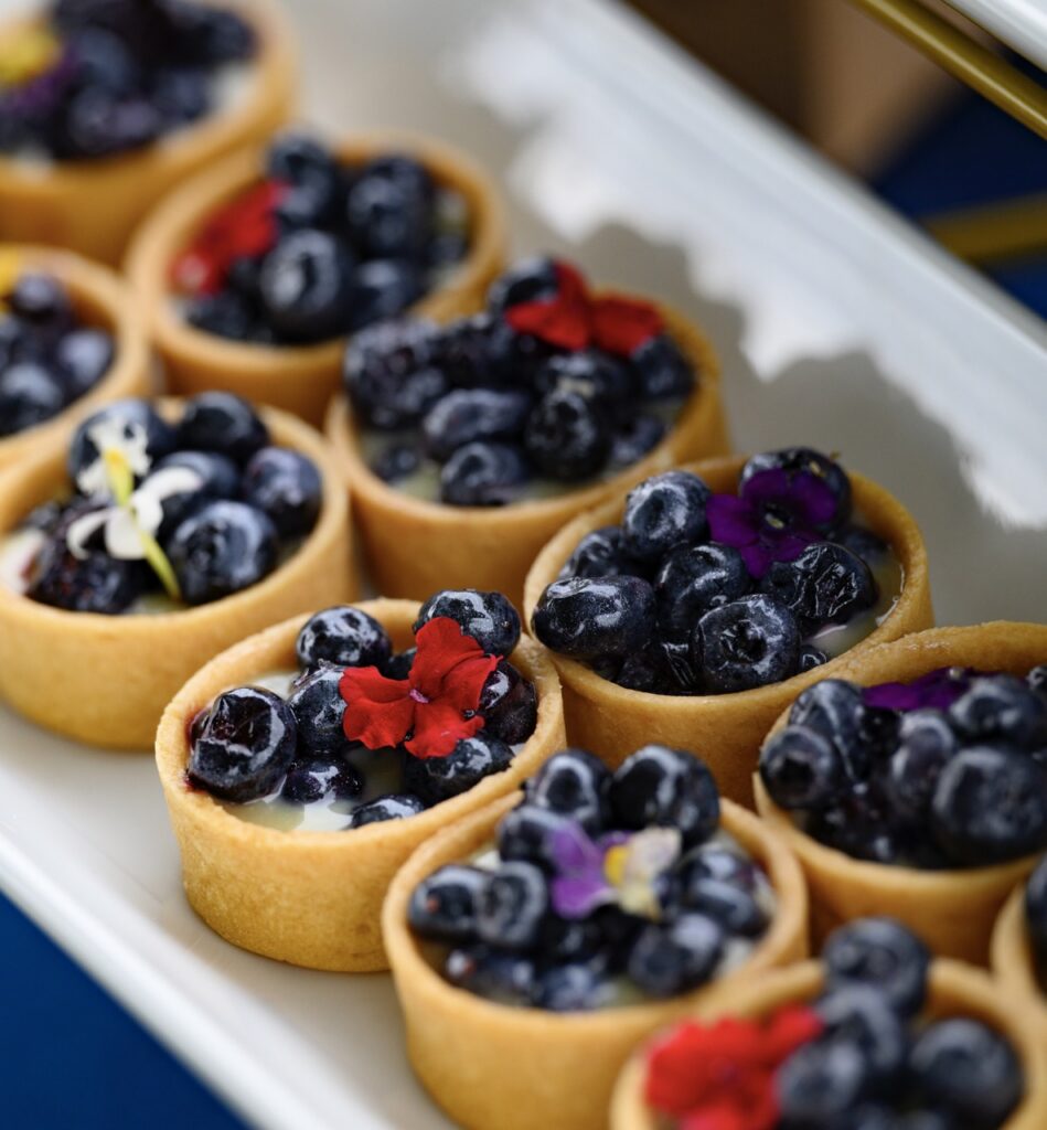 Small blueberry tarts with flowers on top.