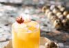 Quail Egg Whiskey Sour A cocktail of a whiskey sour sits on a small tray surrounded by little quail eggs.