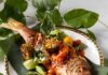 Red Snapper with Taro Root Smash and Salsas A white plate with leaves every where and a red snapper laying on the plate with taro root smash and salsas.