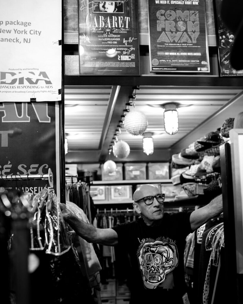 Richard Parsakian leans against two clothes racks.