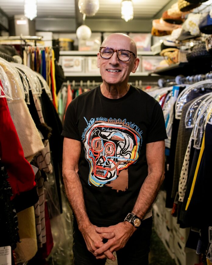 Richard Parsakian stands in his Eons vintage shop between racks of clothes.
