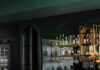 Interior Designer Seashal Belldina Renovates a Basement into a Game Room A bar area with stools sits behind the corner of a pool table with two yellow balls near the corner pocket.