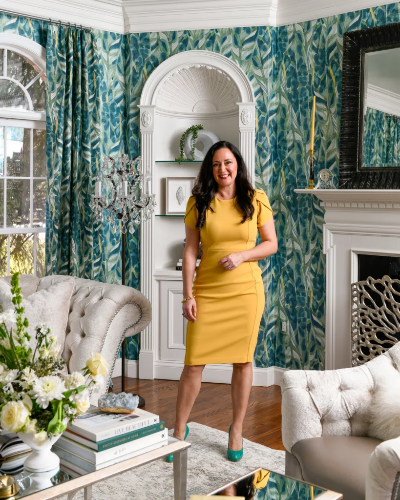 A woman in a yellow dress in a teal wallpaper room.