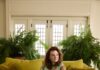 Four Pittsburgh Creatives Style Four Pittsburghers in Spring 2026 Trends A woman in a long mint green dress lounges on an olive green couch.