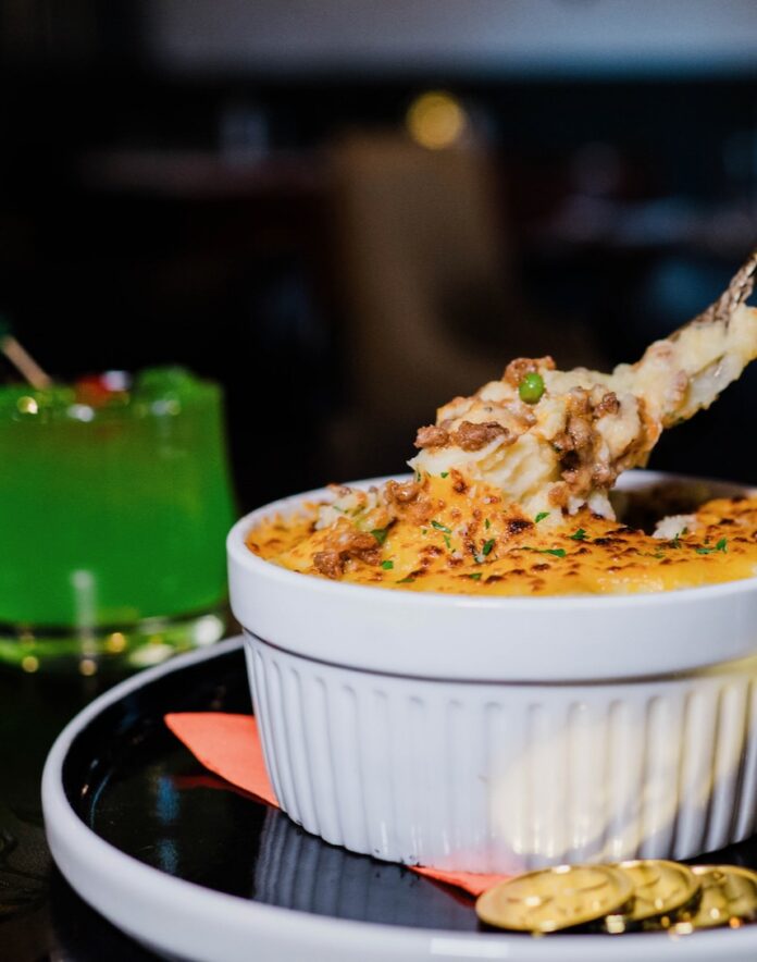 A ramekin of Irish Shepard's pie with a green St. Patrick's Day drink in the background.