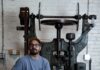 How Studebaker Metals in Pittsburgh is Reviving Handmade Craft A man in a blue shirt and khakis sits in front of an old metal machine.