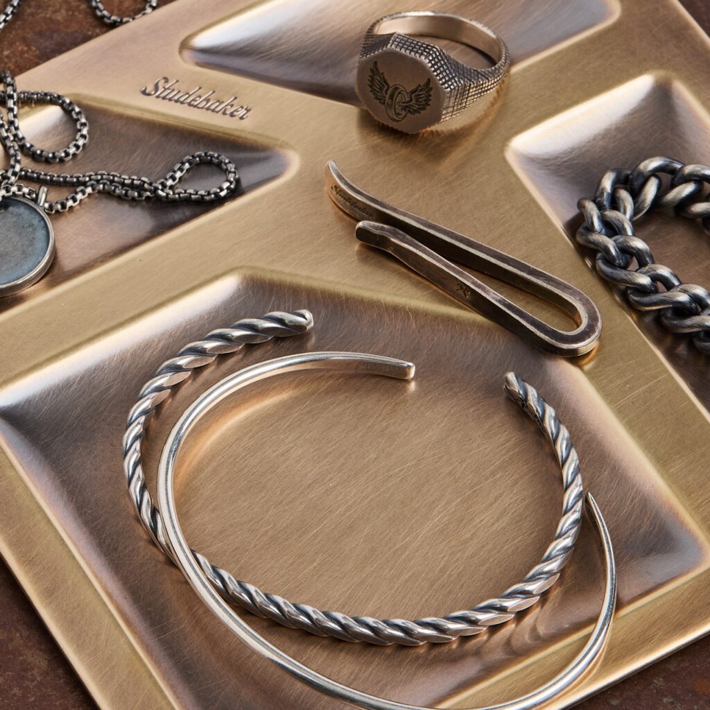 Carious metal bengals, wallet clips, and wings lay on gold metal trays.