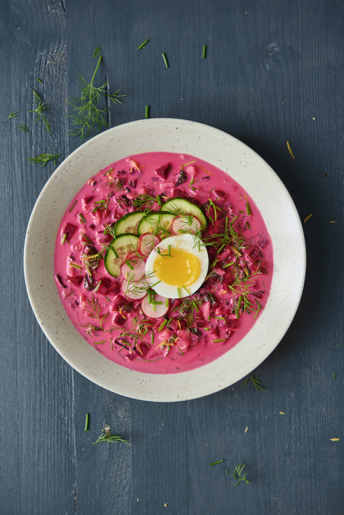 A bowl of pink soup staged over a black background