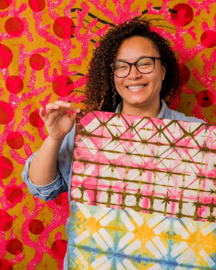 Ghanaian-American textile artist Addoley Dzegede in her Pittsburgh studio, working on a complex warp painting inspired by traditional kente cloth weaving and batik processes.