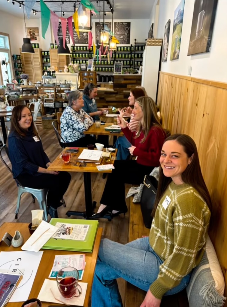 A group of women sit at tables in a cafe.